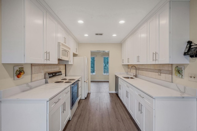 kitchen with white appliances, white cabinets, and a sink