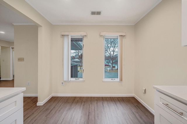 unfurnished dining area featuring light wood finished floors, visible vents, and baseboards