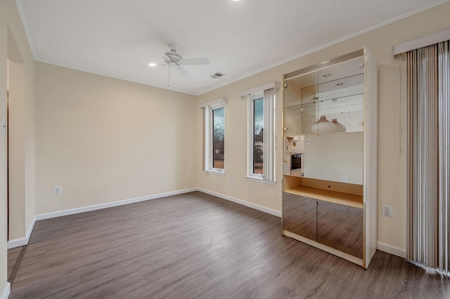 unfurnished bedroom featuring visible vents, ornamental molding, ceiling fan, wood finished floors, and baseboards