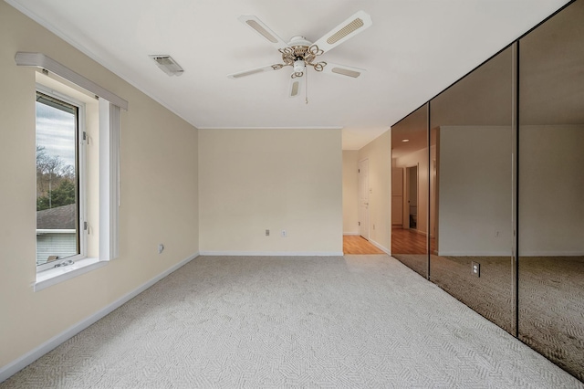 empty room with carpet floors, baseboards, visible vents, and a ceiling fan