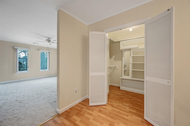 interior space featuring ornamental molding, light carpet, light wood-style flooring, and baseboards