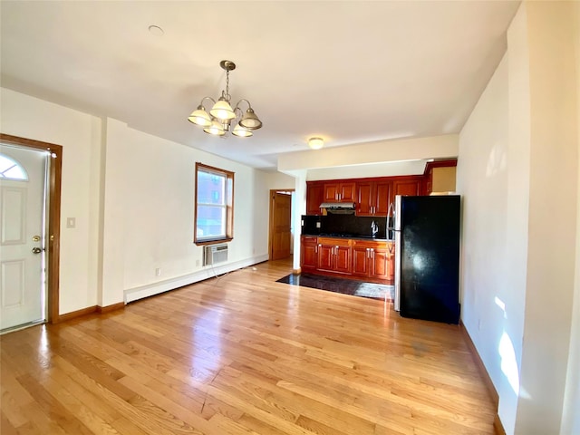 kitchen with light wood-style floors, freestanding refrigerator, under cabinet range hood, a baseboard heating unit, and a notable chandelier