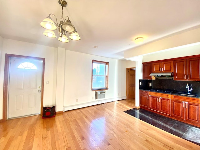 kitchen featuring black gas cooktop, backsplash, dark wood-type flooring, a sink, and under cabinet range hood