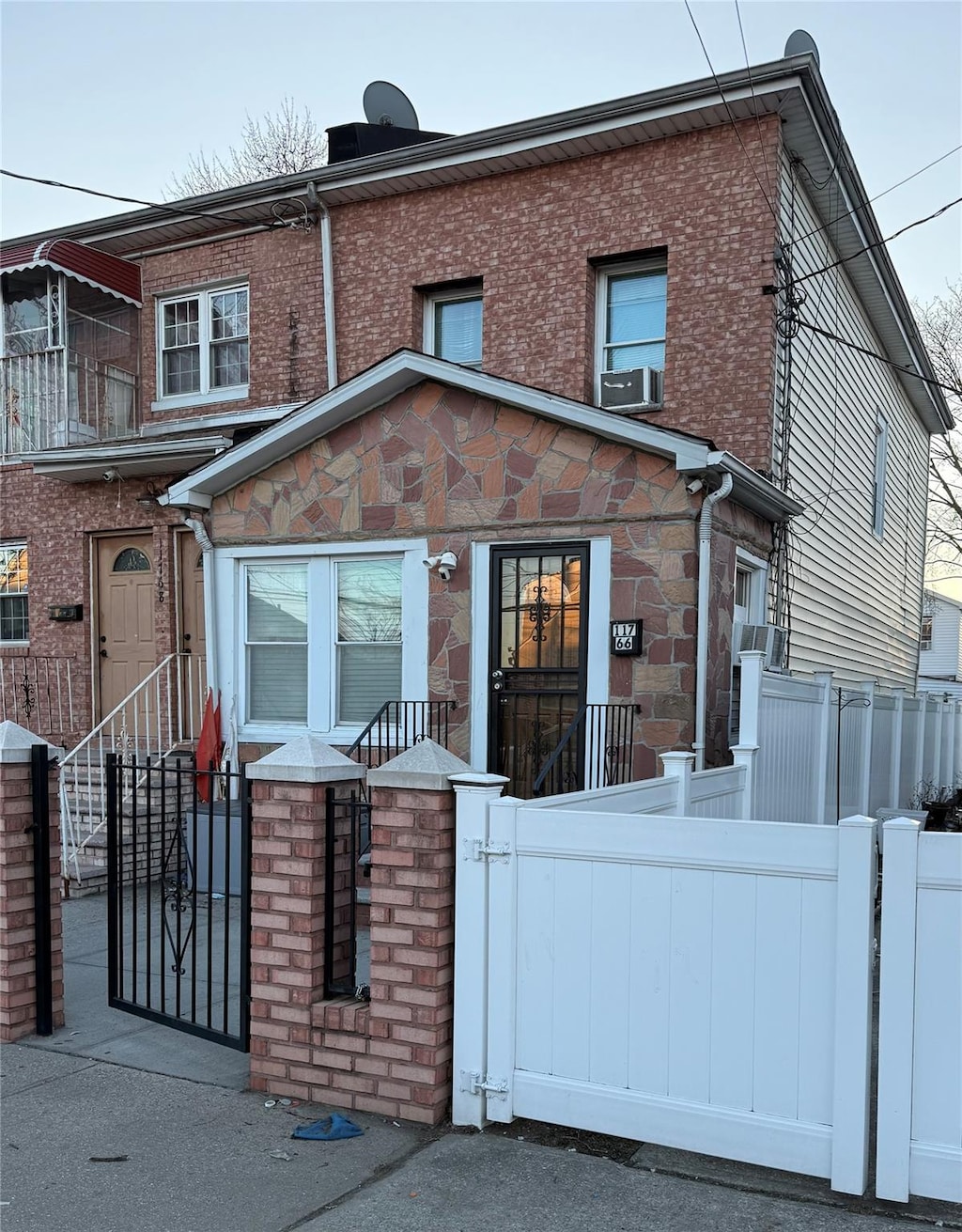 view of front of home featuring stone siding, a gate, and brick siding