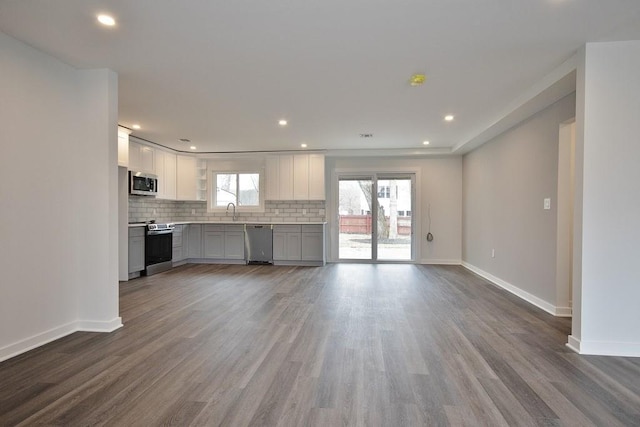 kitchen featuring a sink, appliances with stainless steel finishes, gray cabinets, decorative backsplash, and dark wood finished floors