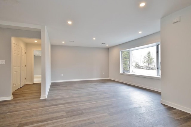 unfurnished room featuring baseboards, wood finished floors, and recessed lighting