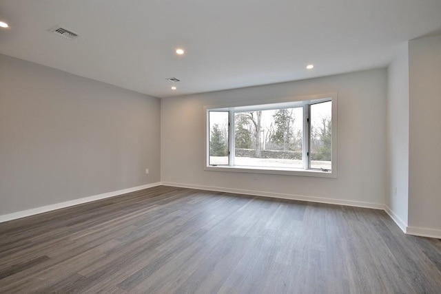 unfurnished room with dark wood-style floors, baseboards, visible vents, and recessed lighting