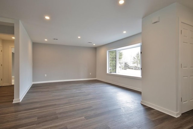 spare room with dark wood-style floors, visible vents, baseboards, and recessed lighting