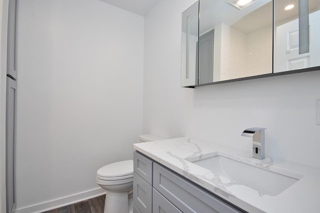 bathroom featuring toilet, wood finished floors, visible vents, vanity, and baseboards