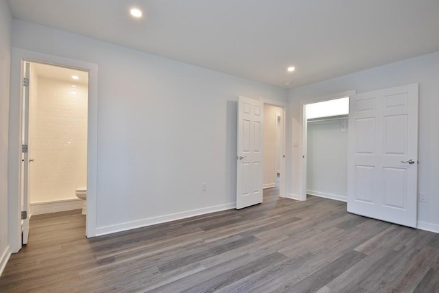 unfurnished bedroom featuring baseboards, connected bathroom, wood finished floors, a closet, and recessed lighting