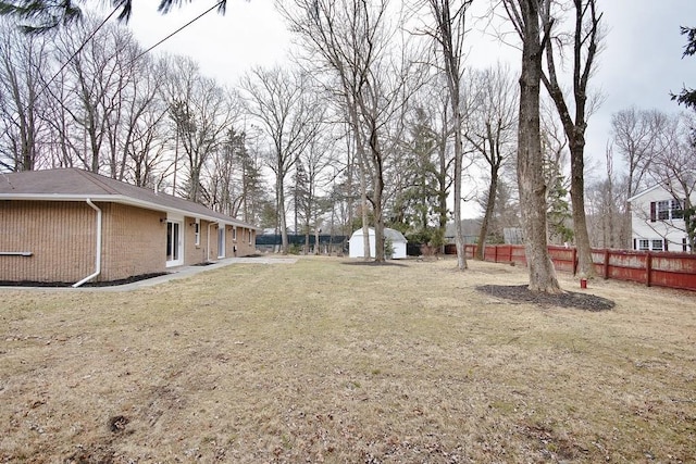 view of yard with fence, an outdoor structure, and a storage unit