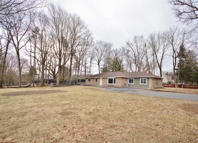 ranch-style home with a front yard, stone siding, and fence