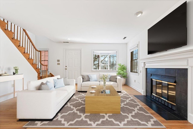 living room featuring a fireplace, recessed lighting, wood finished floors, baseboards, and stairs