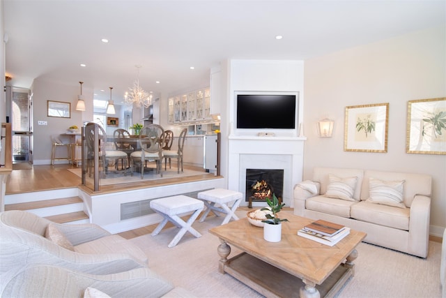 living area with baseboards, light wood finished floors, an inviting chandelier, recessed lighting, and a lit fireplace