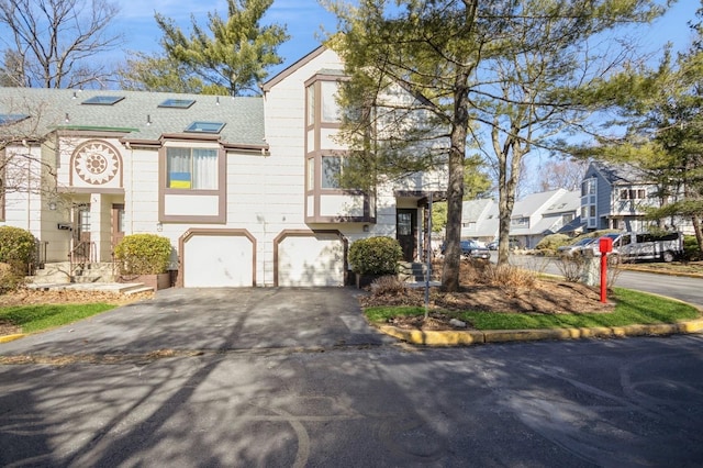 view of front of house featuring aphalt driveway, an attached garage, and a shingled roof