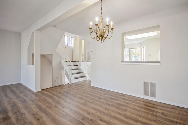 interior space featuring visible vents, wood finished floors, an inviting chandelier, baseboards, and stairs