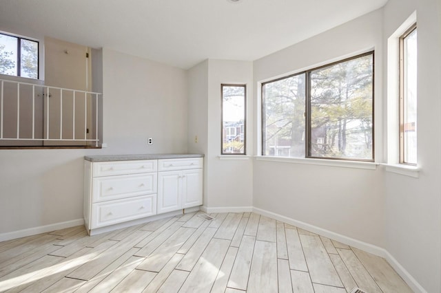 spare room with baseboards and light wood-style flooring