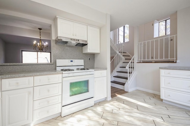 kitchen featuring white gas stove, a chandelier, wood finish floors, and under cabinet range hood