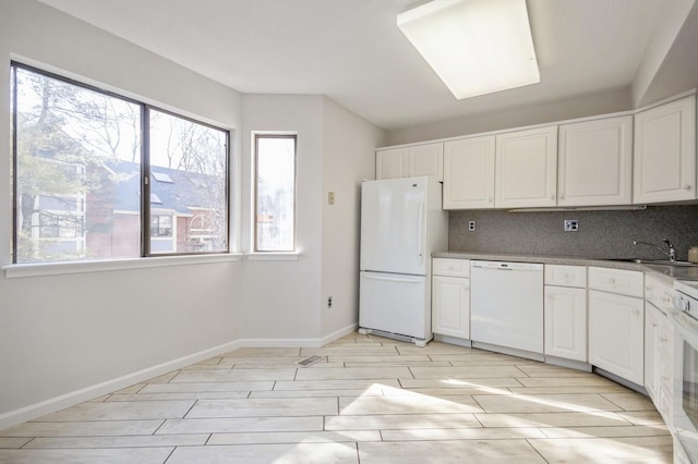 kitchen with tasteful backsplash, white cabinets, white appliances, and a sink