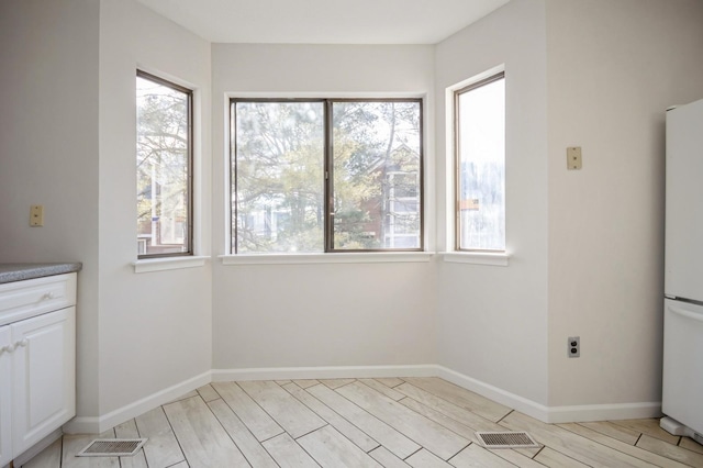 unfurnished dining area featuring visible vents, baseboards, and light wood finished floors