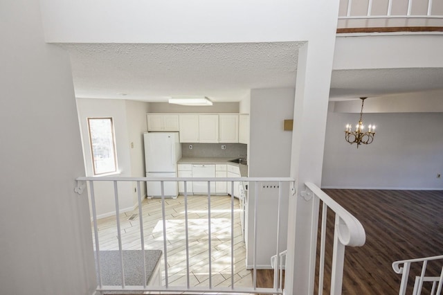 interior space with freestanding refrigerator, light countertops, a textured ceiling, white cabinetry, and backsplash