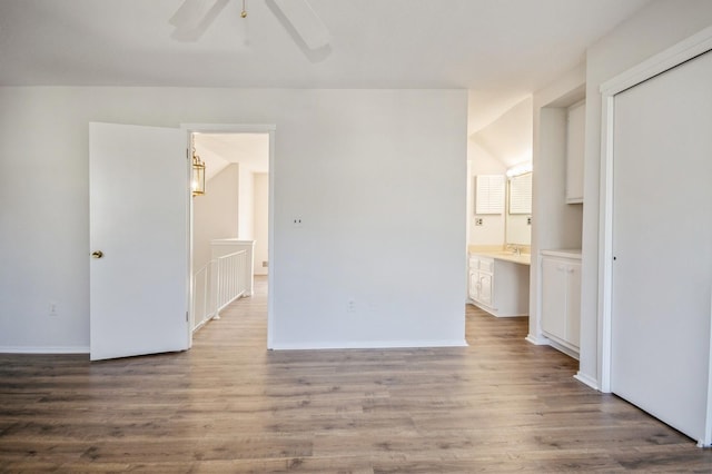 unfurnished bedroom with ceiling fan, baseboards, ensuite bath, and wood finished floors