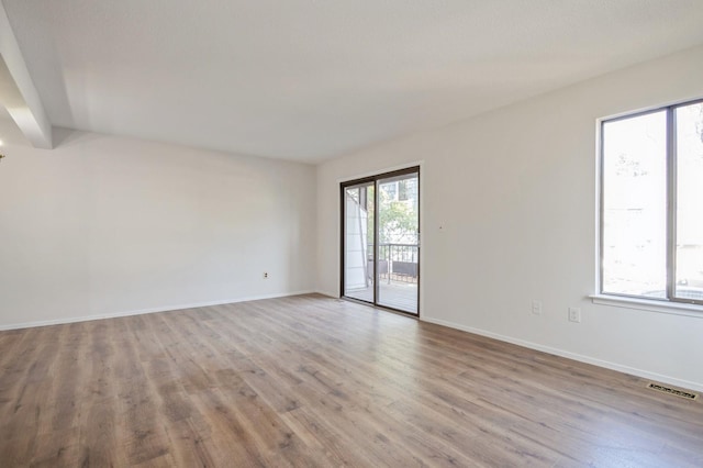 spare room with visible vents, baseboards, and wood finished floors