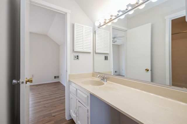 full bath with vanity, wood finished floors, visible vents, baseboards, and vaulted ceiling