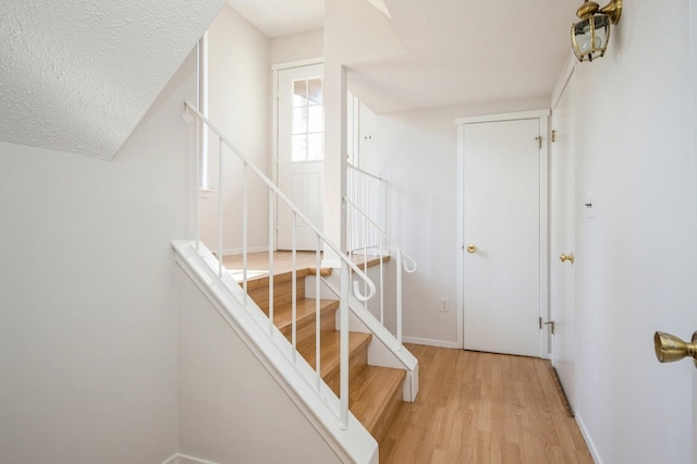 stairs featuring baseboards, a textured ceiling, and wood finished floors