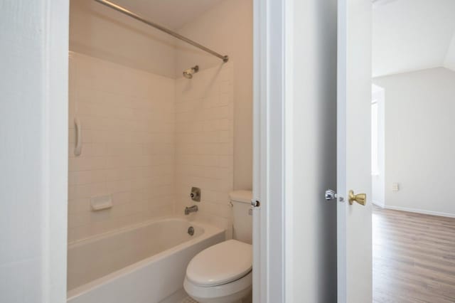 bathroom with washtub / shower combination, wood finished floors, baseboards, vaulted ceiling, and toilet