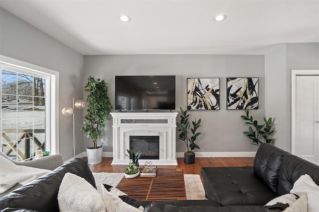 living room featuring recessed lighting, a premium fireplace, baseboards, and wood finished floors