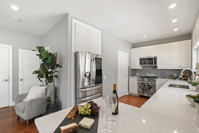 kitchen featuring a sink, white cabinetry, stainless steel appliances, decorative backsplash, and light stone countertops