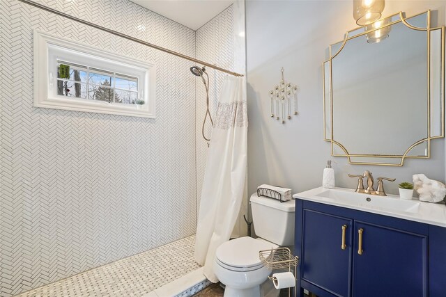 bathroom featuring a tile shower, toilet, and vanity