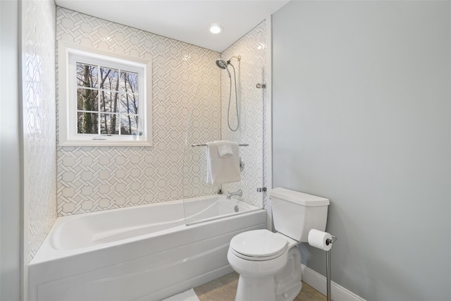 bathroom with shower / bathing tub combination, baseboards, and toilet