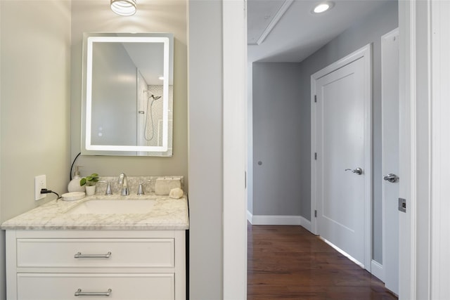 bathroom featuring vanity, wood finished floors, baseboards, recessed lighting, and walk in shower