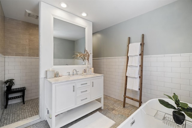 bathroom with a wainscoted wall, visible vents, a soaking tub, recessed lighting, and tile walls