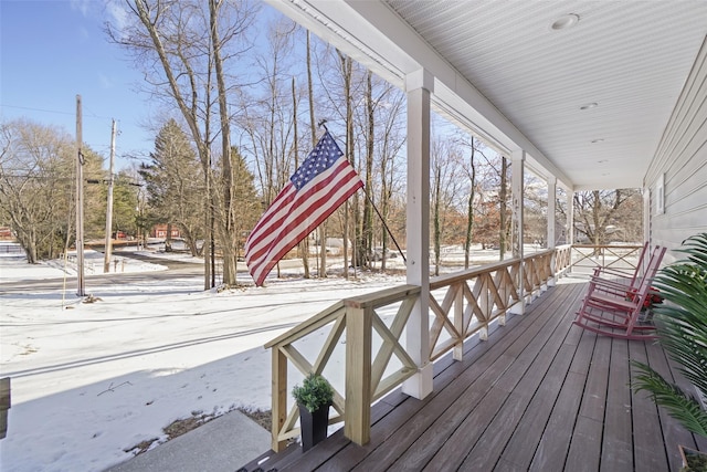 snow covered deck featuring a porch