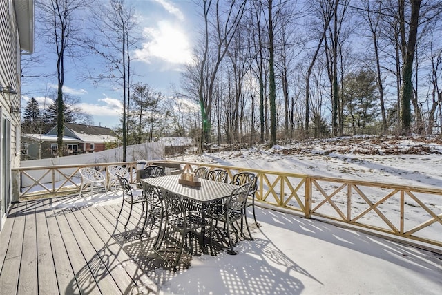 snow covered deck featuring outdoor dining area and fence