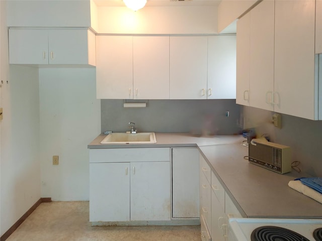 kitchen with light countertops, visible vents, white cabinets, a sink, and baseboards