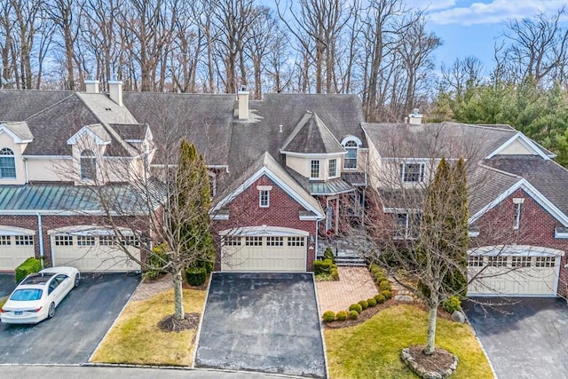 view of front facade with a garage, brick siding, driveway, a front lawn, and a chimney