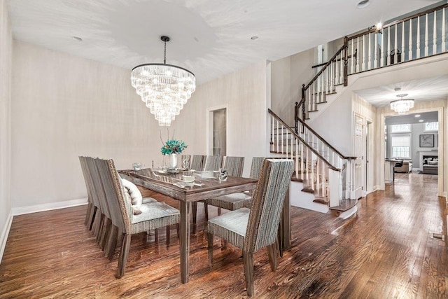 dining area with baseboards, stairs, a chandelier, and wood finished floors