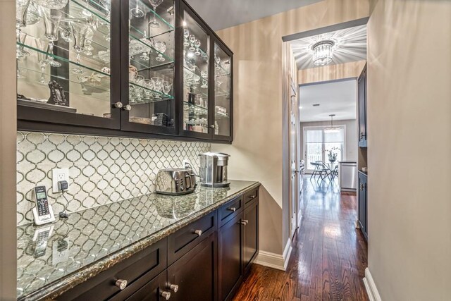 bar with dark wood-style flooring, backsplash, and baseboards