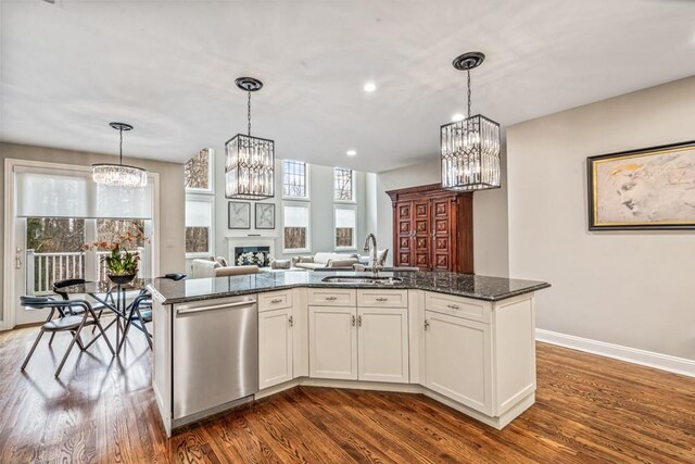 kitchen featuring dishwasher, dark wood-style floors, open floor plan, a fireplace, and a sink