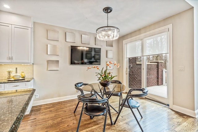 dining area featuring an inviting chandelier, wood finished floors, and baseboards