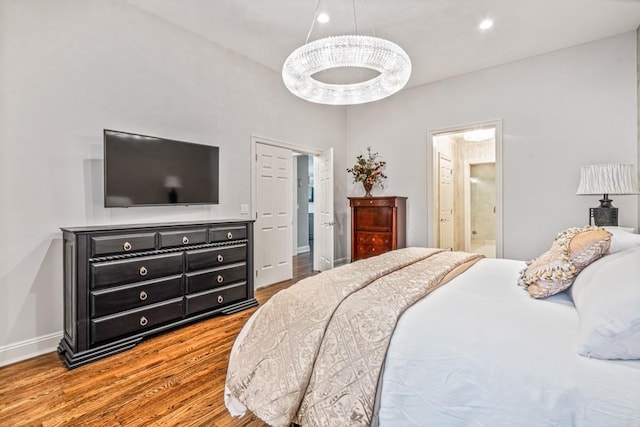 bedroom with baseboards, ensuite bath, wood finished floors, and recessed lighting