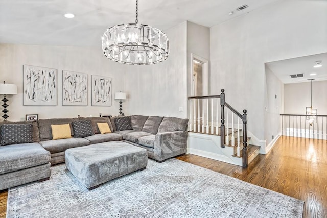 living room featuring baseboards, wood finished floors, visible vents, and an inviting chandelier