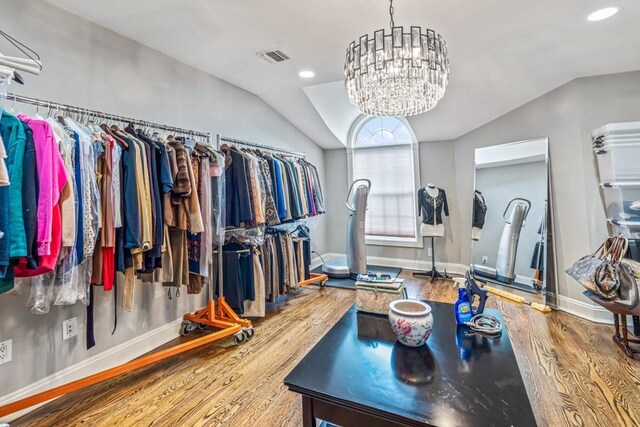 spacious closet featuring an inviting chandelier, visible vents, vaulted ceiling, and wood finished floors