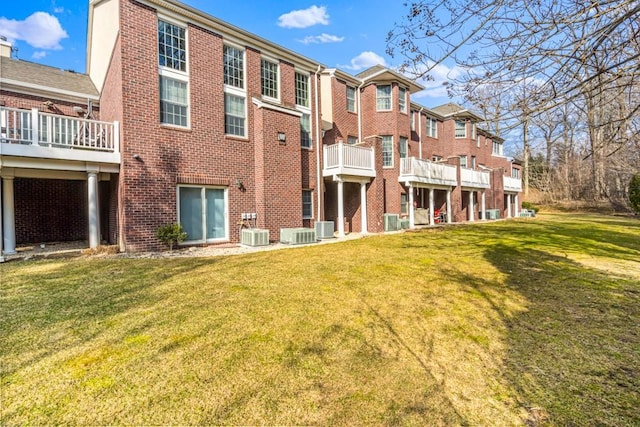 rear view of property featuring brick siding, a yard, and central air condition unit