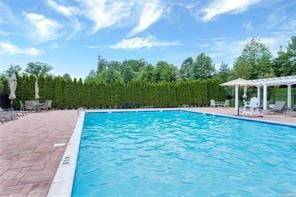 community pool with a patio area and a pergola