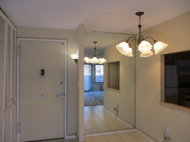 interior space with a chandelier, light tile patterned floors, and baseboards